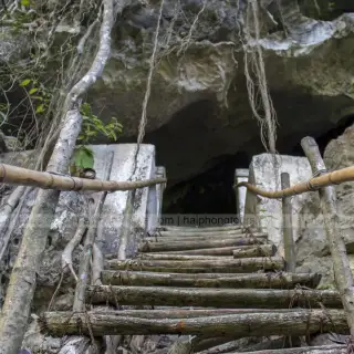 Older photograph of wooden steps and handrails climbing to the entrance of Hospital Cave
