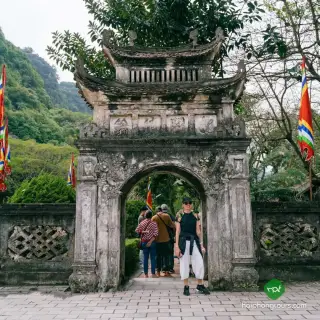 Visitors passing through a carved temple gateway with curved roofs at Hoa Lu Ancient Capital
