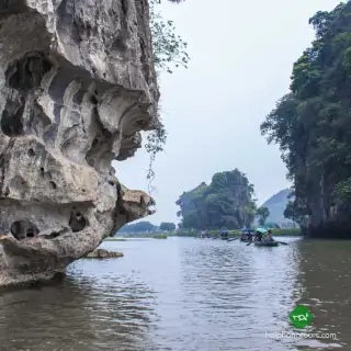 Open rowboats on the Ngo Dong River between limestone cliffs at Tam Coc