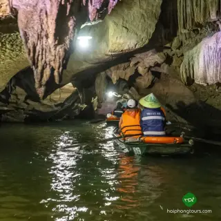 Visitors in a small rowboat beneath limestone formations inside Thanh Truot Cave at Trang An