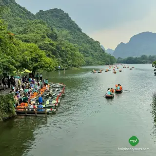 Visitors and rows of small boats beside limestone hills at Trang An boat station