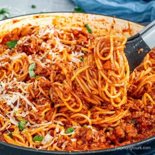 A plate of spaghetti with sauce and grated cheese