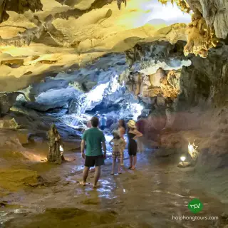 Visitors walking beneath illuminated rock formations inside Thien Canh Son Cave