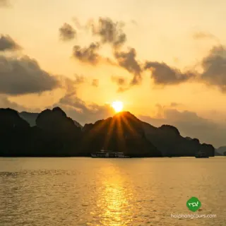 Sunset behind limestone islands and cruise boats on Ha Long Bay