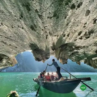 A local rower guiding passengers beneath a limestone arch in the Dark and Bright Cave area