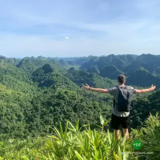 Hiker overlooking forested limestone peaks in Cat Ba National Park