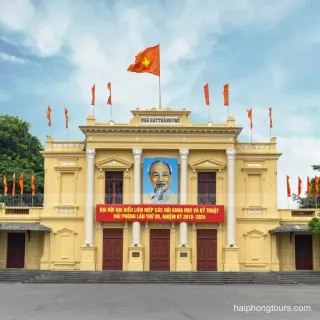 Central facade of Hai Phong Opera House with columns and Vietnamese flags