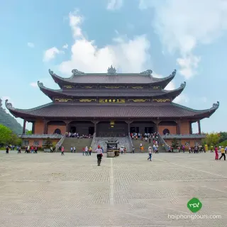 Visitors crossing the broad courtyard toward a large temple hall at Bai Dinh